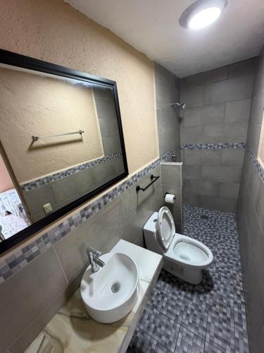 a bathroom with a sink and a toilet and a mirror at Hotel Las Salinas in Zihuatanejo