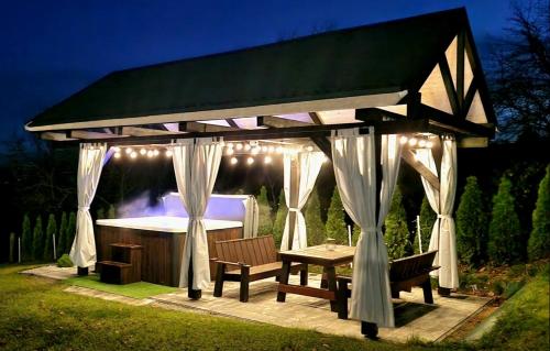 a gazebo with a table and a tub at Domek na Folwarku z jacuzzi in Tarnawa Dolna