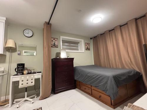 a bedroom with a bed and a dresser and a clock at Private Bachelor Suite Near PNE in Vancouver