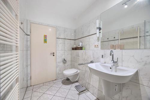 a white bathroom with a sink and a toilet at Ferienhaus an der Luhe 150 M² in Winsen