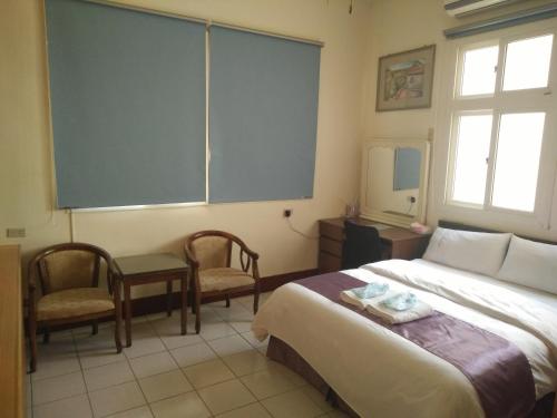 a hotel room with a bed and two chairs at Frank B&B in Jincheng