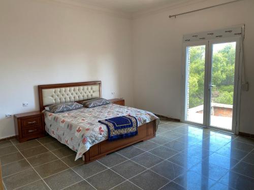 a bedroom with a bed and a large sliding glass door at villa larhat vue sur mer in Larhat