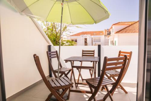 a table and chairs with an umbrella on a balcony at Casa Caravelas - Matias Village in Praia da Areia Branca