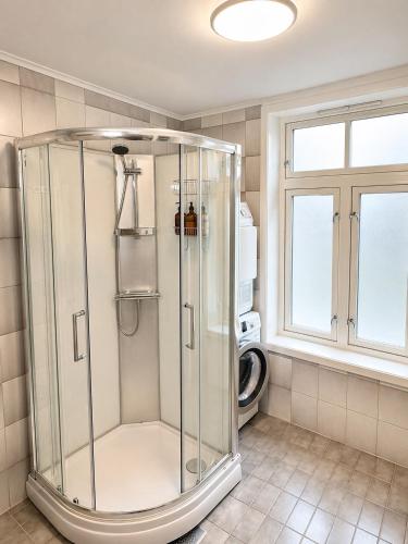 a glass shower in a bathroom with a window at Stor attraktiv studioleilighet i sentrum in Trondheim