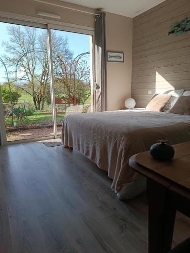 a bedroom with a bed and a large window at Une escale gourmande- Suite avec terrasse & dîner maison possible in Eyzerac