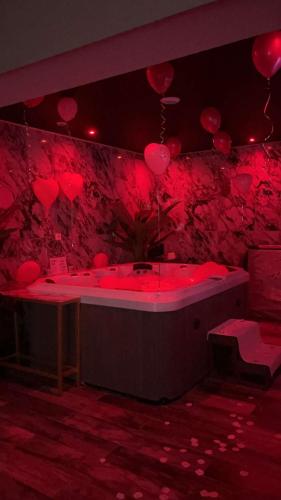 a room with a tub with red balloons on the wall at Why Not Jacuzzi in Arles