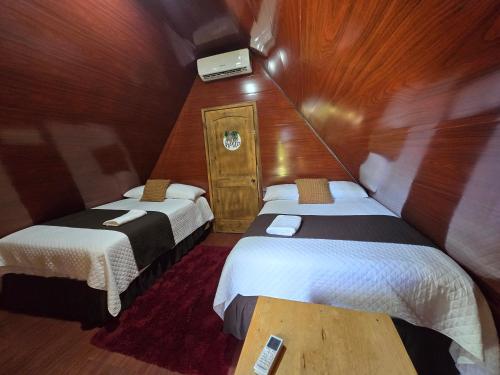 a small room with two beds and a tv at Cabañas Villa Aurora in Campamento