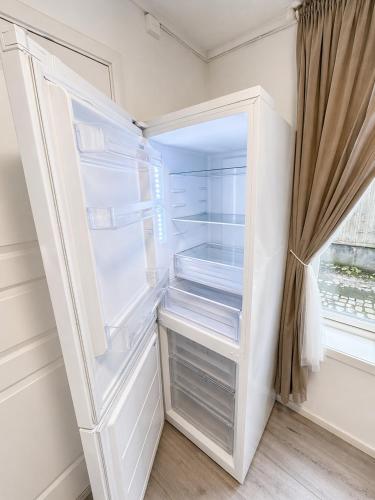 an empty refrigerator with its door open at Stor attraktiv studioleilighet i sentrum in Trondheim
