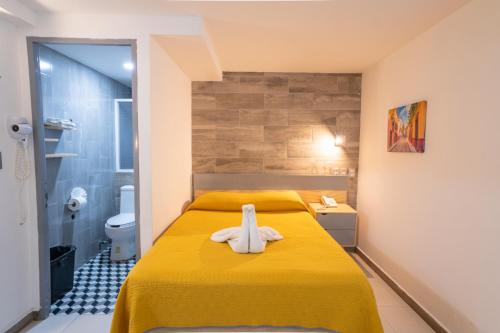 a bedroom with a yellow bed and a bathroom at El Suburbio - Morelos Sur in Morelia