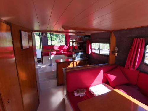a train car with red seats and a table at Peniche Maryjeanne in Gannay-sur-Loire