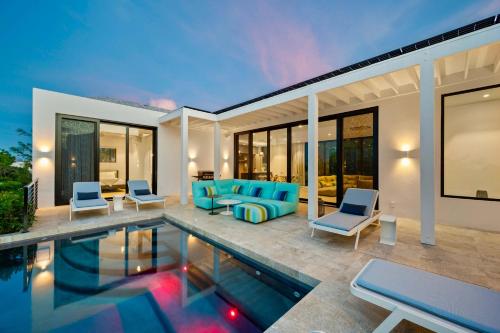 a villa with a swimming pool and blue furniture at Skyline Villas - Villa Luna Oceanfront with Private Pool in Providenciales