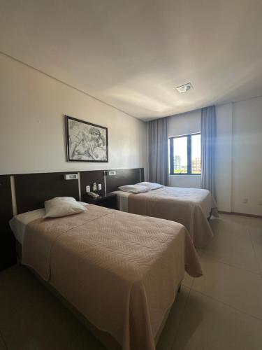 a hotel room with two beds and a window at Hotel Palace Frederico in Frederico Westphalen
