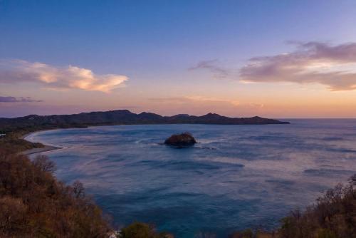 an island in the middle of the ocean at sunset at Wake Up to the Pacific, Concierge Included in Playa Flamingo
