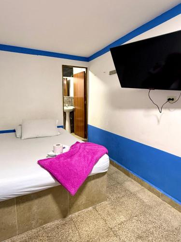 a bedroom with a bed with a pink blanket at Hotel Sol y Luna 2 in Medellín