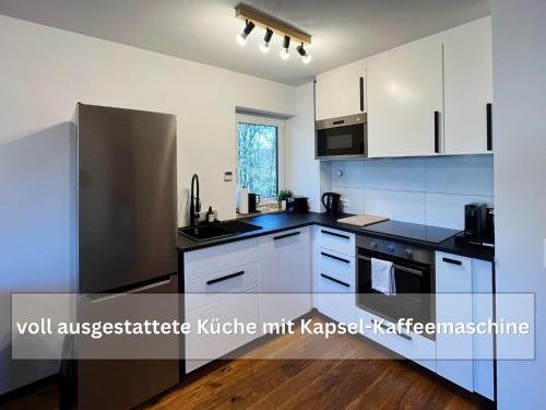 a kitchen with white cabinets and a stainless steel refrigerator at Ruhige Ferienwohnung Seemöwe mit Balkon - ideal für Paare & Radurlauber in Radolfzell am Bodensee