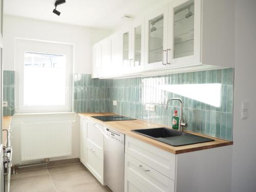 a kitchen with white cabinets and a sink at Ferienhaus mit Panoramablick in Ohlsdorf