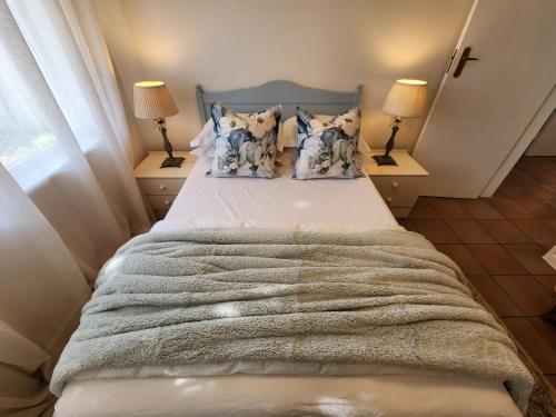 a bedroom with a large bed with two lamps at At Let Se Plek in Jeffreys Bay
