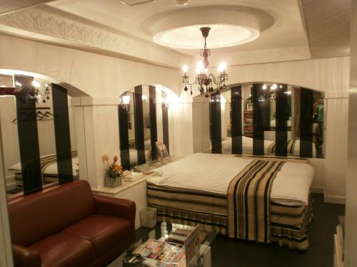 a bedroom with a bed and a couch and a chandelier at Hotel Piatt (Adult Only) in Nagoya