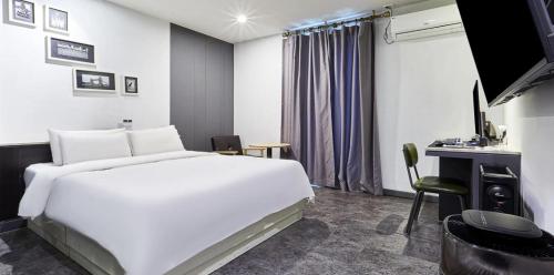 a hotel room with a large white bed and a desk at 월호텔 in Pyeongtaek