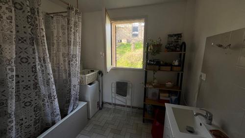 a bathroom with a tub and a sink and a window at L'Ombre du pommier in Paron