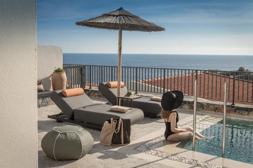 a woman sitting next to a swimming pool with an umbrella at Abas Villas in Paránimfoi