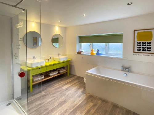 a bathroom with a tub and a sink and mirror at The Oaks in Blackburn