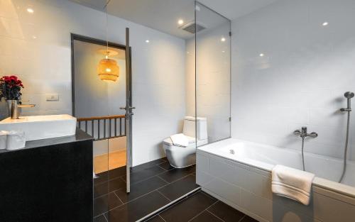 a bathroom with a tub and a sink and a toilet at Villa Sonata Phuket in Chalong 