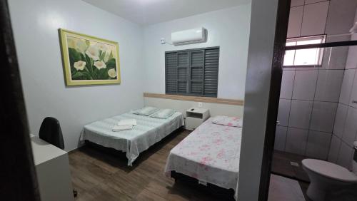 a small room with two beds and a window at Hotel Calema in Capitão Leônidas Marques