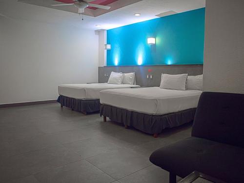 two beds in a room with a blue wall at Hotel MX portal maya in Playa del Carmen