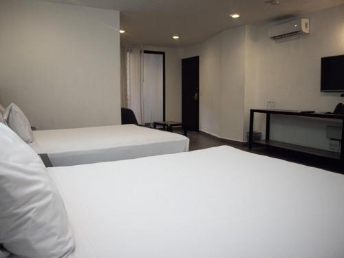 a hotel room with two beds and a desk at Hotel MX portal maya in Playa del Carmen