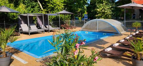 a pool with chairs and umbrellas in a yard at Doris Hotel in Siófok