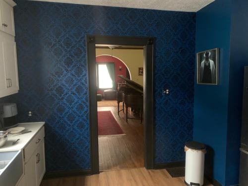 a kitchen with blue walls and a door to a dining room at Dr. Yaple's Art Deco House in Lafayette