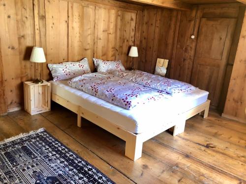 a bed in a room with wooden walls and wooden floors at BnB Villa Kapellmatt - Seezugang, Bio-Frühstück, SUP am Rigi in Vitznau