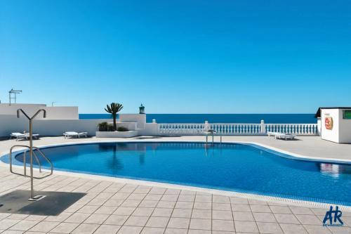 a swimming pool in a resort with the ocean in the background at Arthouse Sea View - Acquamarina e Zaffiro in Puerto del Carmen