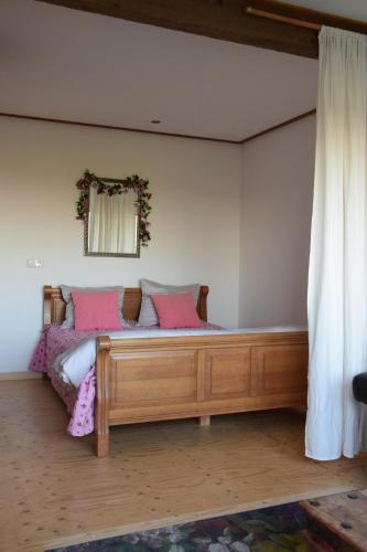 a bedroom with a wooden bed with pink pillows at Maison Zélandaise in Koudekerke