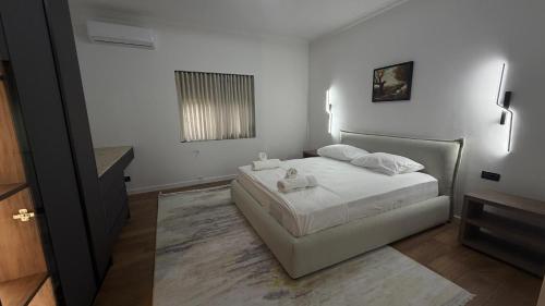 a bedroom with a bed with white sheets and a window at Solemar4 in Vlorë