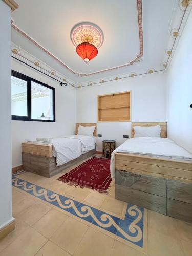 a bedroom with two beds and a chandelier at Le petit château Vue sur mer Uniquement les familles in Oualidia