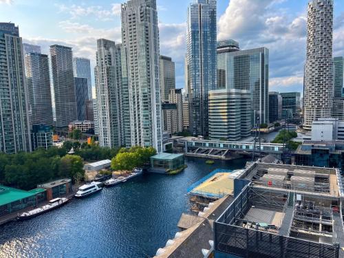 a river in a city with tall buildings at London Canary Wharf Luxury Stay in London
