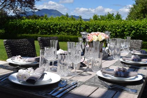 a wooden table with plates and glasses on it at Bellevue Boutique Lodge in Taupo