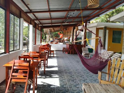 a patio with tables and hammocks in a restaurant at Miraflores Beach Lodge in Santo Domingo