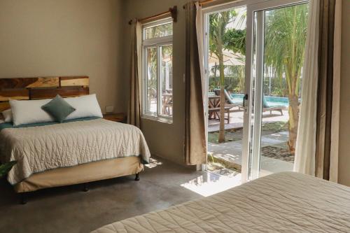 a bedroom with two beds and a sliding glass door at Gecko Hotel in El Paredón Buena Vista