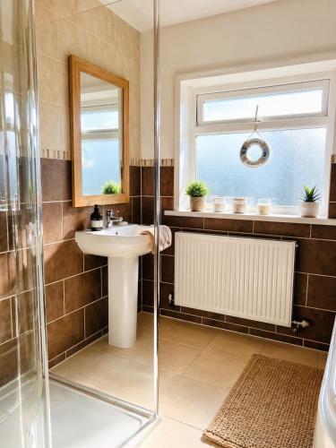a bathroom with a sink and a shower at Old Post Office By The Sea in Allonby