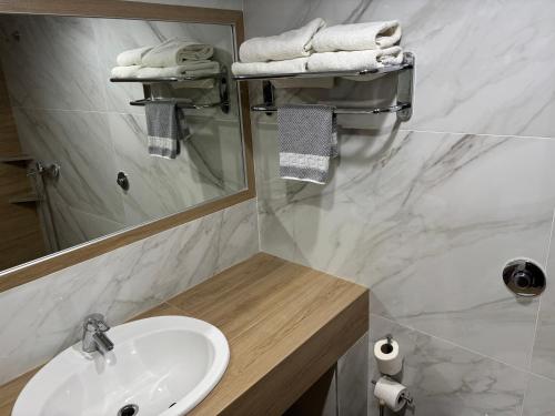 a bathroom with a sink and a mirror and towels at Achillio Hotel in Komotini