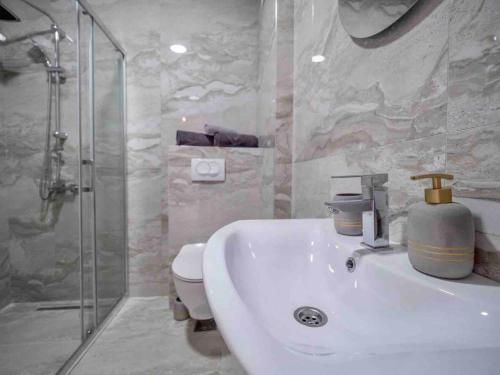 a bathroom with a sink and a shower and a toilet at Becici Chic 1BR Condo swimming pool long term in Budva