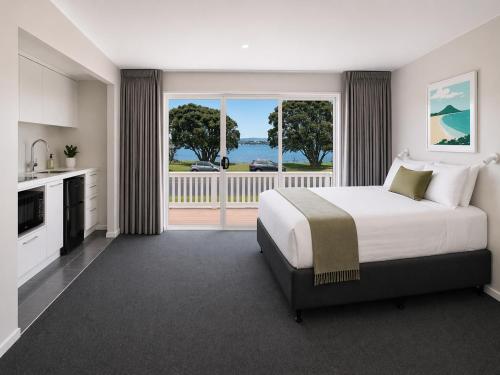 a bedroom with a large bed and a balcony at Tauranga Backpackers - Private Guest Rooms by the Water! in Tauranga