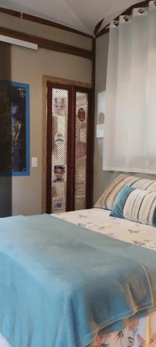 a bedroom with a bed and a window with curtains at Chalé Hidro Jurerê in Florianópolis