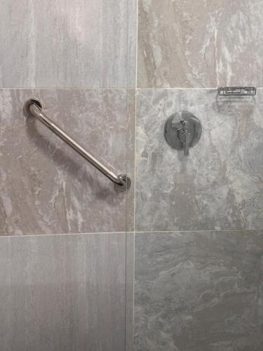 a shower with a glass door with a shower handle at Sunset Heaven in Newcastle