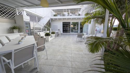 a restaurant with white tables and chairs and palm trees at Arneo Terra del Sole B&B in Torre Lapillo