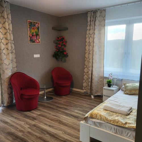 a bedroom with two red chairs and a bed and a window at Jaworina- Apartamenty, Domki i Pokoje in Solina