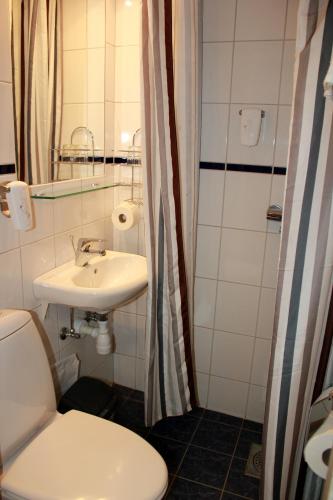 a bathroom with a white toilet and a sink at Grand Hotel Arendal - Unike Hoteller in Arendal